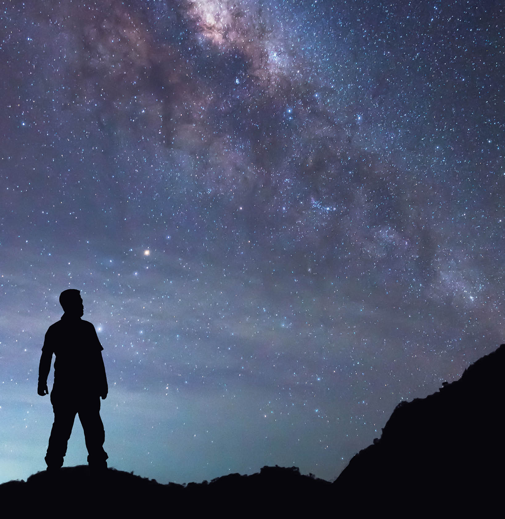A person is standing and seeing Milky Way galaxy on night sky.